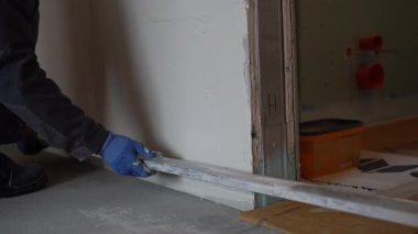 Zeminin altından, bir erkek sıva ustası elinde metal bir kural tutuyor ve yeni sıvanmış duvarı hizalıyor. Yüksek kalite 4k görüntü
