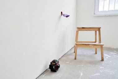 Elektrik prizi tamamlanmamış, kablolar mor elektrik bandıyla sarılmış. Lazer teçhizatının yanında ahşap bir tezgah. Kopyalanacak bir yer var. Yüksek kalite fotoğraf