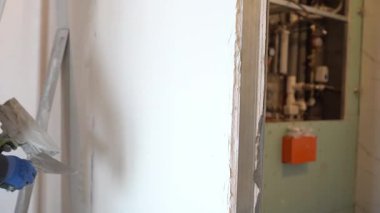Adamın biri spatulaya sıva koyuyor. Duvardaki alçı tabakasını metal bir spatulayla düzleştiriyorum. Tadilat ve inşaat kavramı. Yüksek kalite 4k görüntü
