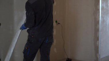 Daire tadilatı. Duvarları ölçen bir adamın elinde metal bir kural vardır. Yüksek kalite 4k görüntü