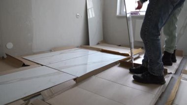 Zanaatkarlar kalıba uyması için fayansları dizerler. Duvarlara 120 'ye 60 boyutlarında geniş formatlı porselen döşeme. Yüksek kalite 4k görüntü