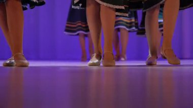 Sahnedeki bacaklara yakın çekim. Rus halk dansları sahnesinde performans. Geleneksel Rus kıyafetleri içindeki çocuklar sahnede dans ediyorlar. Yüksek kalite 4k görüntü