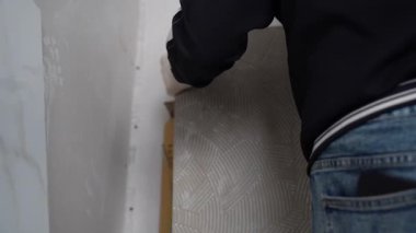 Fayanslardaki desenlere uyuyor. Bir adam duvarın diğer tarafına geniş formatlı bir fayans yerleştiriyor. 120 'ye 60 fayans döşeme hazırlığı. Yüksek kalite 4k görüntü