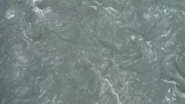 Çamurlu nehri alüvyondan dinamik bir şekilde hareket ettiren bir yere yakın plan. Vahşi nehir. Vahşi yaşam. Suda köpük var. Yüksek kalite 4k görüntü