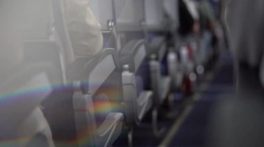 Gökkuşağını yansıtan bir prizmanın bulanık görüntüsü. Uçağın rahat kabinindeki yolcu koltuklarının arasındaki koridorda. Yüksek kalite 4k görüntü