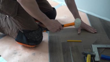 Tanınmayan bir adam ringa kemiği desenli bir kuvars vinil döşemesi serer. Yeni evin parke zemini çok güzel. Yeni bir dairede kuvars vinil fayans. Yüksek kalite 4k görüntü