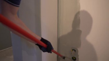 Boya silindirli duvar boyası. Boyayı tutarken el hareketi. Yüzeyde gri boya var. Yüksek kalite 4k görüntü