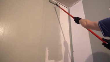 Tamirci mükemmel bir duvar resmi için duvarları bir yığın rulosuyla boyuyor. Tepeden tırnağa patinaj hareketi. Yüksek kalite 4k görüntü