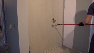 Mükemmel duvar boyası için boya silindirli duvarlar. Tepeden tırnağa patinaj hareketi. Yüzeyde gri boya var. Yüksek kalite 4k görüntü