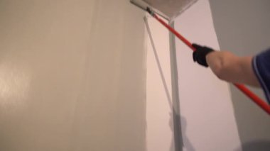 Mükemmel duvar boyası için boya silindirli duvarlar. Tepeden tırnağa patinaj hareketi. Yüzeyde gri boya var. Yüksek kalite 4k görüntü