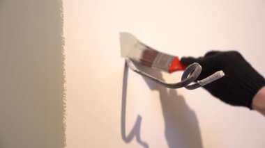 Duvarları telin etrafına fırçayla boyamak. Daire tadilatı. Duvardan siyah bir elektrik kablosu sarkıyor. Yüksek kalite 4k görüntü