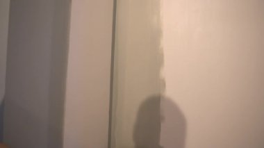 Mükemmel bir duvar resmi için bir adam boya rulosuyla duvar boyuyor. Tepeden tırnağa patinaj hareketi. Yüzeyde gri boya var. Yüksek kalite 4k görüntü