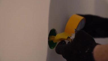 Sarı bantlı kabloların yalıtımı. Duvarları boyamadan önce. Elektrik bağlantısı ve plastik prizlerin onarımı ve kurulumu için hazırlık. Yüksek kalite 4k görüntü