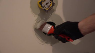 Priz açıklarının yakınındaki duvarları fırçayla boyamak. Daire tadilatı, elektrik bağlantısına hazırlık ve plastik prizlerin kurulumu. Yüksek kalite 4k görüntü