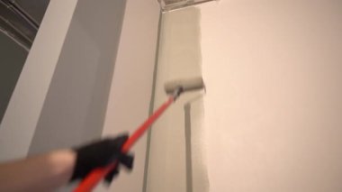 Mükemmel duvar boyası için boya silindirli duvarlar. Tepeden tırnağa patinaj hareketi. Yüzeyde gri boya var. Yüksek kalite 4k görüntü