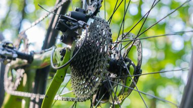 Yeşil arka planda bir bisikletçi çıplak elleriyle şanzımanı tamir ediyor.