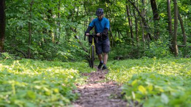 Bisikletçi ormanda bir patikaya biniyor.