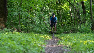 Bisikletçi ormanda bir patikaya biniyor.