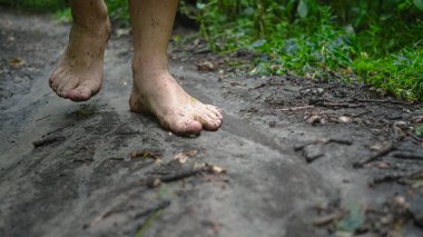 İnsan doğada yalın ayak, orman yolu ve çimlerle yürür.