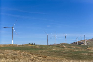 Mavi gökyüzü olan bir tepede rüzgar türbinleri