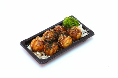Takoyaki, mayonez, soya sosu, beyaz arka planda siyah bir tabakta deniz yosunu serpiştirilmiş..