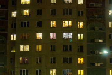 Çok katlı bir binanın gece pencereleri. Konut binasının aydınlık ve koyu pencereleri