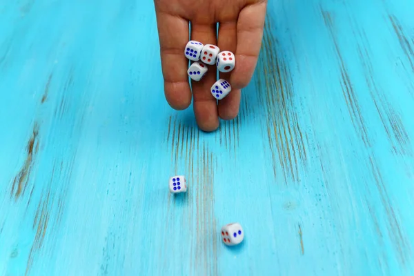 The hand rolls dice for the game. Gambling luck concept: best, risk, have luck, win, lucky. Blue wooden background