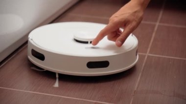 Evi temizlemek için robot elektrik süpürgesinin güç düğmesine basar. Seçici odaklanma. Akıllı Ev