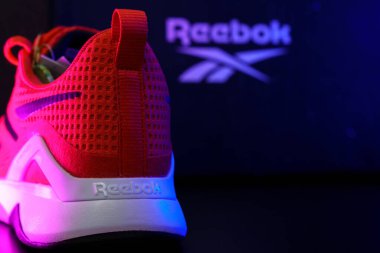 Tyumen, Rusya-Ağustos 03, 2023: Spor için şık kırmızı Reebok ayakkabıları. Çok renkli ışık. Seçici odaklanma. Boşluğu kopyala