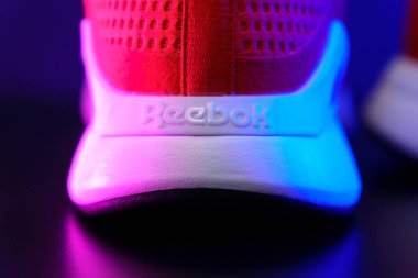 Tyumen, Rusya-Ağustos 03, 2023: Kırmızı Reebok logosu yakın model Nanoflex spor ayakkabıları, koşu ayakkabıları. Çok renkli ışık. Seçici odak