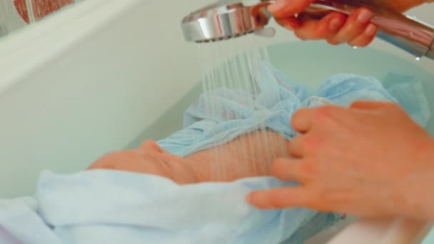 母亲用温水在宁静的浴室环境中清洗新生儿 关注婴儿的安全和舒适 — 图库视频影像