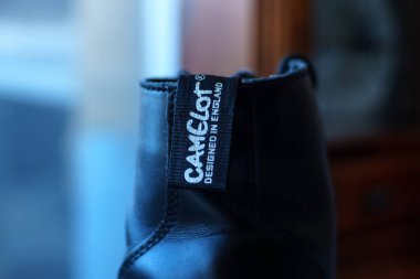 Üzerinde Camelot marka etiketi olan siyah bir ayakkabı. Ayakkabının eşsiz markasını gösteriyor..