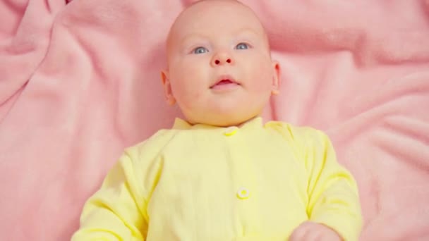 Bayi Muda Berpakaian Kuning Berbaring Atas Selimut Merah Muda Lembut — Stok Video