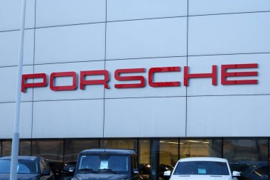 Tyumen, Rusya-18 Mart 2024: Porsche bayiliğinin önüne park edilmiş araçlar, lüks arabalar ve ikonik Porsche logosu sergileniyor..