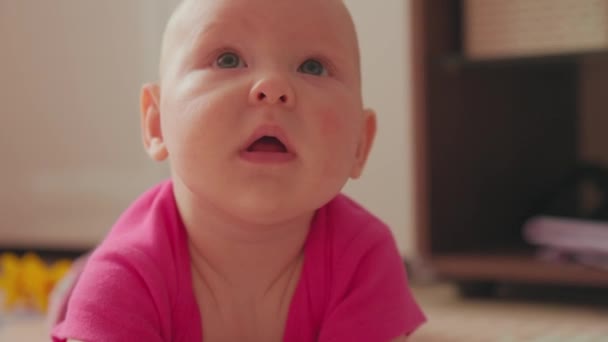 ピンクのシャツの赤ちゃんの笑顔は平和的に床にあり 静けさの瞬間をベースにしています — ストック動画