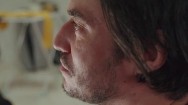 Saçları dağınık bir adam, parlak renkler ve eşsiz dekorasyonlarla süslenmiş canlı bir odada dikilirken şaşkın bir yüz ifadesi sergiler.