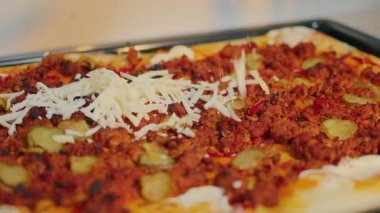 Lezzetli et, taze sebze ve sıcak bir mutfak ortamında erimiş peynirli ev yapımı pizza.