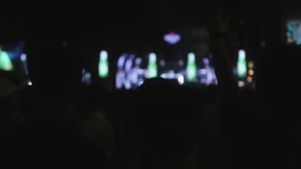 夜のストリートコンサートでギタリストとドラマーとロックバンド 群集はパーティーを投げ踊っている ファンのシルエットは 上の明るいカラフルなストロボライトの前で手を上げる — ストック動画