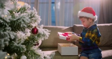 Mutlu şirin çocuk, sürprizle mutlu, Noel 'de hediyelerle dolu bir kutuyu açıyor. Güzel bir çocuğun portresi, içinde sürpriz bir Noel ruhu olan bir kutu açar, bayramlar ve kutlamalar.