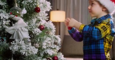 Mutlu küçük kız Noel ağacını toplarla süslüyor. Ağacın altında bir sürü hediye kutusu var. Çocuklar Noel ağacı süslüyorlar. Noel 'de Noel ağacının yanında bir çocuğun portresi