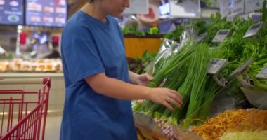 Çekici genç kadın yeşil soğan seçiyor, süpermarketten alışveriş yapıyor, sağlıklı yiyecekler alıyor, marketten yeşil soğan alıyor, süpermarketten. Market kavramı