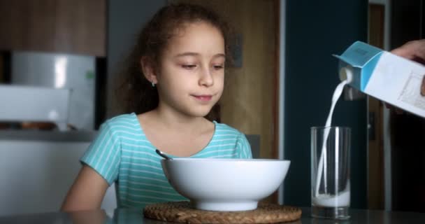 爸爸为他的女儿斟满牛奶 乳制品早餐的概念 孩子们早上喝新鲜的牛奶 把牛奶倒入透明的杯子里 玻璃杯里倒入牛奶 — 图库视频影像