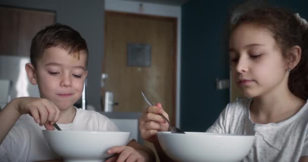 孩子们正坐在厨房桌子边吃早饭和燕麦片 早晨健康的早餐 快乐的童年 — 图库视频影像