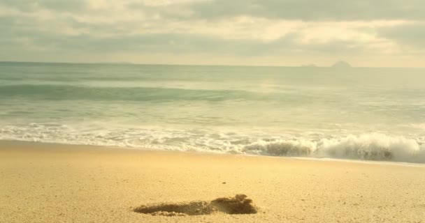 アジアのビーチの背景 砂の中の波の上の太陽の軌跡 大きな太陽は雲の後ろから現れ 大きな山は地平線と海岸に触れる — ストック動画