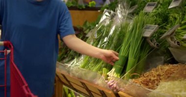 Çekici genç kadın yeşil soğan seçiyor, süpermarketten alışveriş yapıyor, sağlıklı yiyecekler alıyor, marketten yeşil soğan alıyor, süpermarketten. Market kavramı