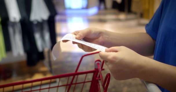 妇女在购物中心购物后 通过在购物车中检查亲爱的金额账单来检查纸质支票 食品价格上涨 在超级市场上花钱 妇女检查购物车 — 图库视频影像