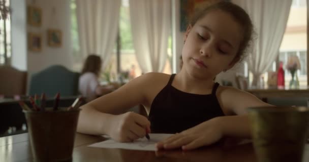 幸せな子供の女の子10歳は自宅でリラックスし 自宅に座って色鉛筆で紙の上に描画します 白人の子供が家で絵を描く — ストック動画
