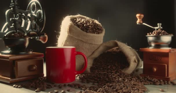 コーヒーカップとコーヒー豆 ホットコーヒーとコーヒー豆の一握り 4Kの暗い背景にヴィンテージのエスプレッソグラインダーを備えたコーヒーマグカップが出てくる自然煙を蒸すクローズアップ — ストック動画