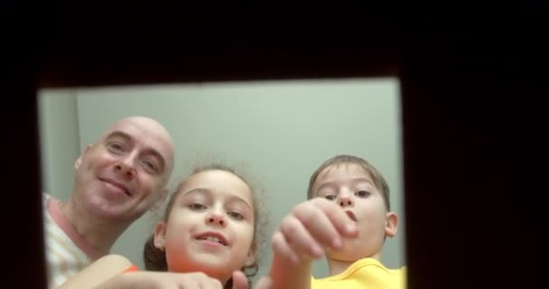 快乐的爸爸和他的孩子们 喜出望外 打开一个装有礼物的盒子 小孩子 女孩和一个兄弟 在一个纸板箱里看着 孩子们把手伸进箱子里 — 图库视频影像