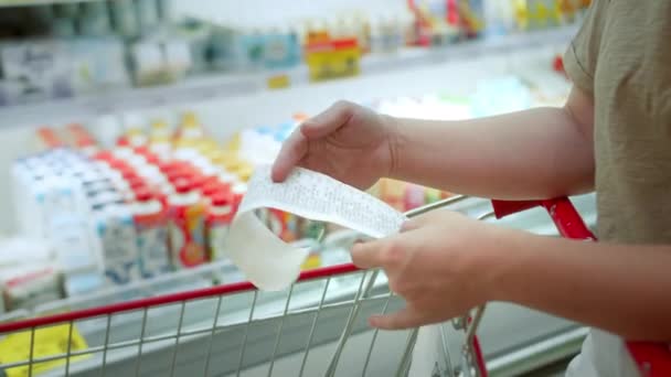 妇女在购物中心购物后 通过在购物车中检查亲爱的金额账单来检查纸质支票 食品价格上涨 在超级市场上花钱 妇女检查购物车 — 图库视频影像